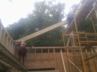 Carpenter raising a rafter beam on a new second story frame in Dillon