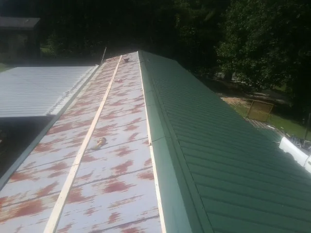 Old rusted panels beside newly installed green metal roofing — Wind Damage Roof Repair by Roofing Brothers in Dillon